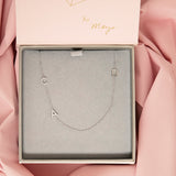 A Custom Gold Necklace in white gold with three letters, a pavé C and A on the left side and a D on the right side, in a Maya Brenner case against a pink fabric background.