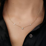 Gold necklace with "C", "M", "T", a birthstone and a heart charm on a person wearing a black shirt.