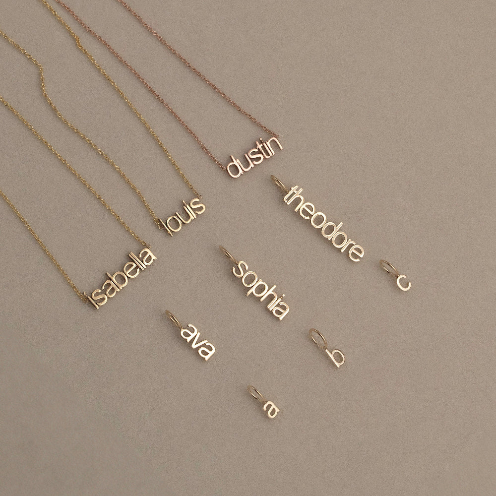 Gold name necklaces on a beige background