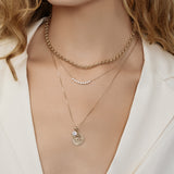 Close up of model wearing the zodiac necklace styled with other gold necklaces.