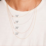 Four gold initial necklaces around a women's neck shown in different lengths.