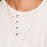 Four gold initial necklaces around a women's neck shown in different lengths.