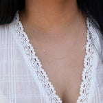 A close-up of a woman's neck wearing a gold necklace with a letter J charm.
