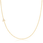 A gold necklace with a pave letter A charm on a white background.