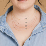 A close-up of a woman's neck wearing 4 necklaces with single letter charms A, B, C and D in various lengths.