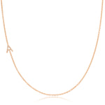 A rose gold necklace with a pave letter A charm on a white background.