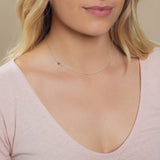 Close-up of a woman's neck wearing a white gold necklace with a letter K charm.