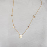 Gold necklace with various charms on a light gray fabric background