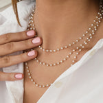 Close-up of a neck wearing multiple The Lily Bouquet Necklaces with a white shirt. 