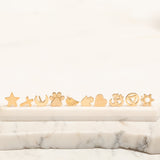 Several Charm Studs – Star, Cross, Moon, Paw, Angel Wing, Hamsa, Heart, Om, Recovery and Star of David laid on a marble stone surface and a white background. 