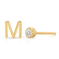 A yellow gold monogram earring set, featuring a mini letter M stud and a mini diamond stud on a white background. 