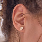 Close-up of an ear wearing a Pavé Charm Stud - Paw. 