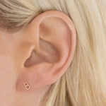 Close-up of a 14K Gold Number Stud in rose gold and 8 in a blonde woman's ear. 