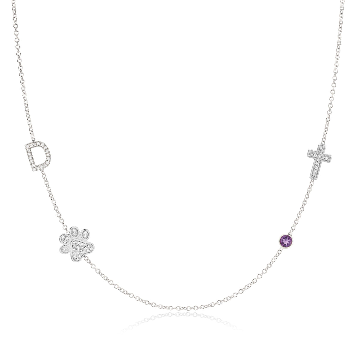 A Custom Gold Necklace in white gold with four charms, a pavé D and a paw positioned on the left side of the necklace, and a pavé cross and birthstone positioned on the right, on a white background.