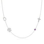 A Custom Gold Necklace in white gold with four charms, a pavé D and a paw positioned on the left side of the necklace, and a pavé cross and birthstone positioned on the right, on a white background.