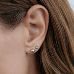 Close-up of a white gold Mini Preppy Post and Preppy Post in a brunette woman's ear. 