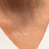 Close-up of a décolletage wearing a GIGI Necklace in white gold with a cable chain, with a white knit top. 