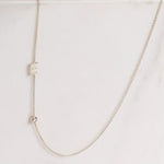 A Monogram Necklace with Diamond White Gold and a letter E charm on a light grey background. 