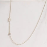 A Monogram Necklace with Diamond White Gold and a letter E charm on a light grey background. 