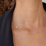 A close-up of a woman's neck wearing a white gold 14k Gold Asymmetrical Charm Necklace - Paw with a cable chain, styled with a black jacket. 