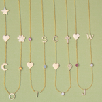 Four Custom Gold Necklaces in yellow gold, three with five different charms and one with six, laid against a light green background.