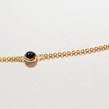 A yellow gold 14K Gold Asymmetrical Birthstone Necklace - Onyx (August) laid on a white surface. 