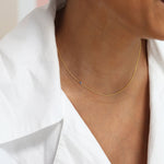 A close-up of a person's neck wearing a yellow gold 14K Gold Asymmetrical Birthstone Necklace - Sapphire (September), styled in a white shirt.