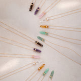 Several Retreat Necklaces in various colours on a cream soft-textured background.