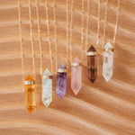 Six Retreat Necklaces (Happiness, In Flow, Healing, Love, Courage and Clarity) on a wooden background. 