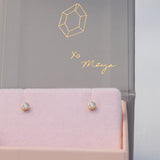A pair of Birthstone Studs - Diamond (April) in a Maya Brenner jewellery box against a light grey background. 