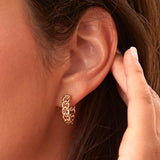 Close-up of a yellow-gold Link Hoop in a brunette woman’s ear.