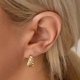Close-up of an Etched Paris Earring on a blonde woman's ear. 