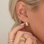 Close-up of an Etched Paris Earring, Double Ear Cuff, Etched Paris Ring and The Evermore Ring being worn by a blonde woman against a cream background. 