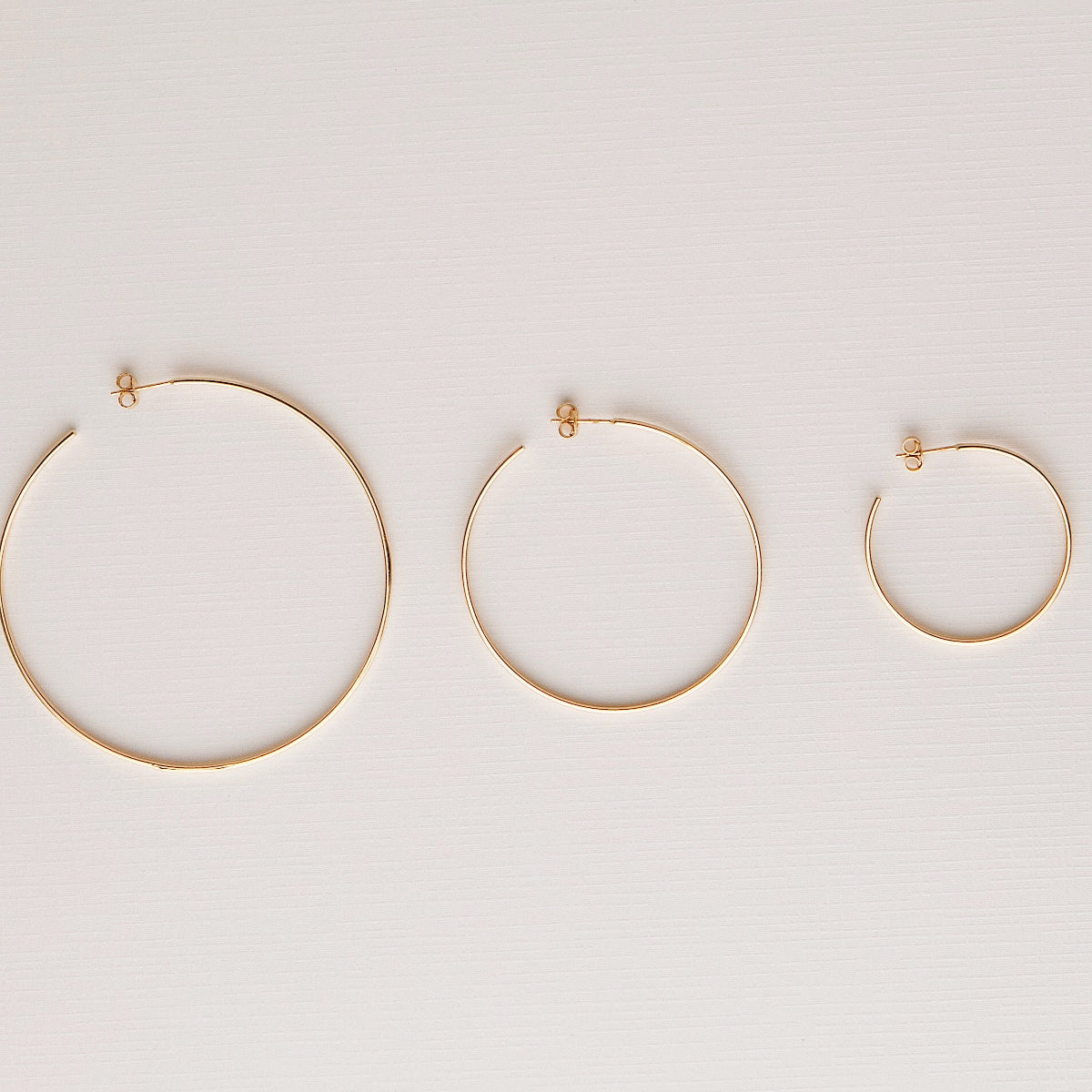 Sleek & Chic Hoops in small, medium and large against an off-white background.  