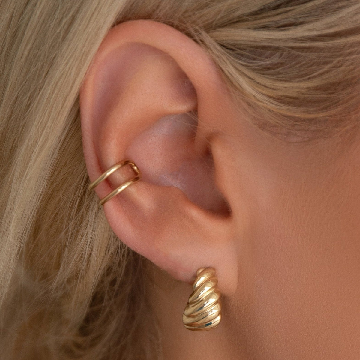 Close-up of an Etched Paris Earring and Double Ear Cuff on a blonde woman's ear. 