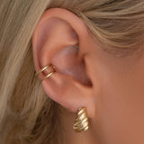 Close-up of an Etched Paris Earring and Double Ear Cuff on a blonde woman's ear. 