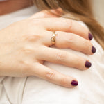 A close-up of a woman’s hand wearing two Letter Rings, G and F, and a Birthstone Ring.