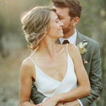 Couple embracing outdoors with the woman wearing a Zodiac Necklace - Libra and a Simple Bangle with a blurred natural background. 