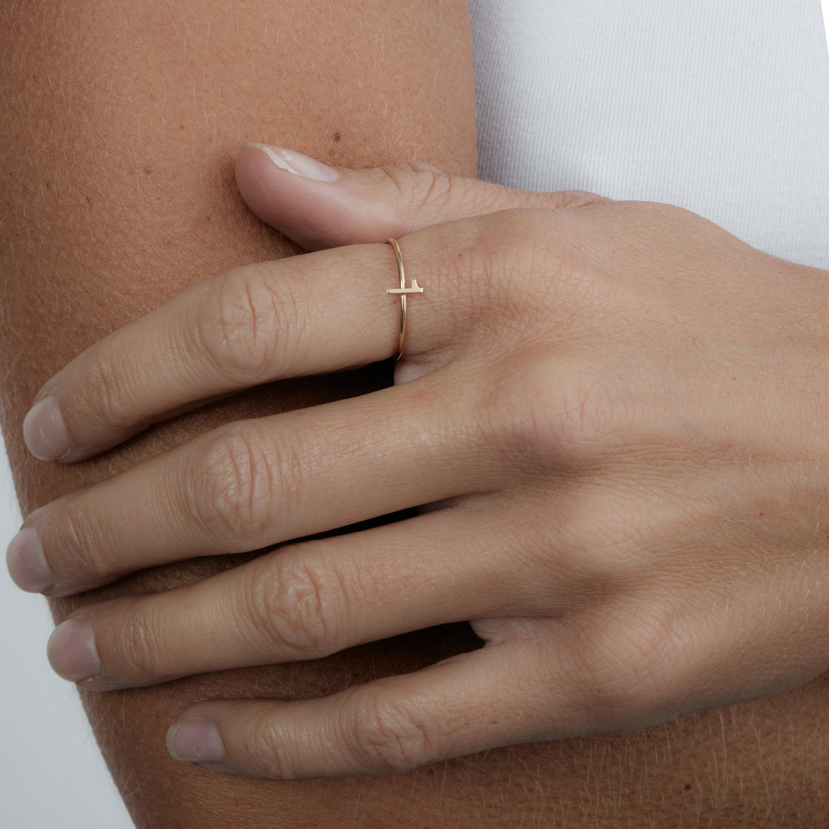 Close-up of a hand wearing a yellow gold Lucky Number Ring in 1 against a white background. 