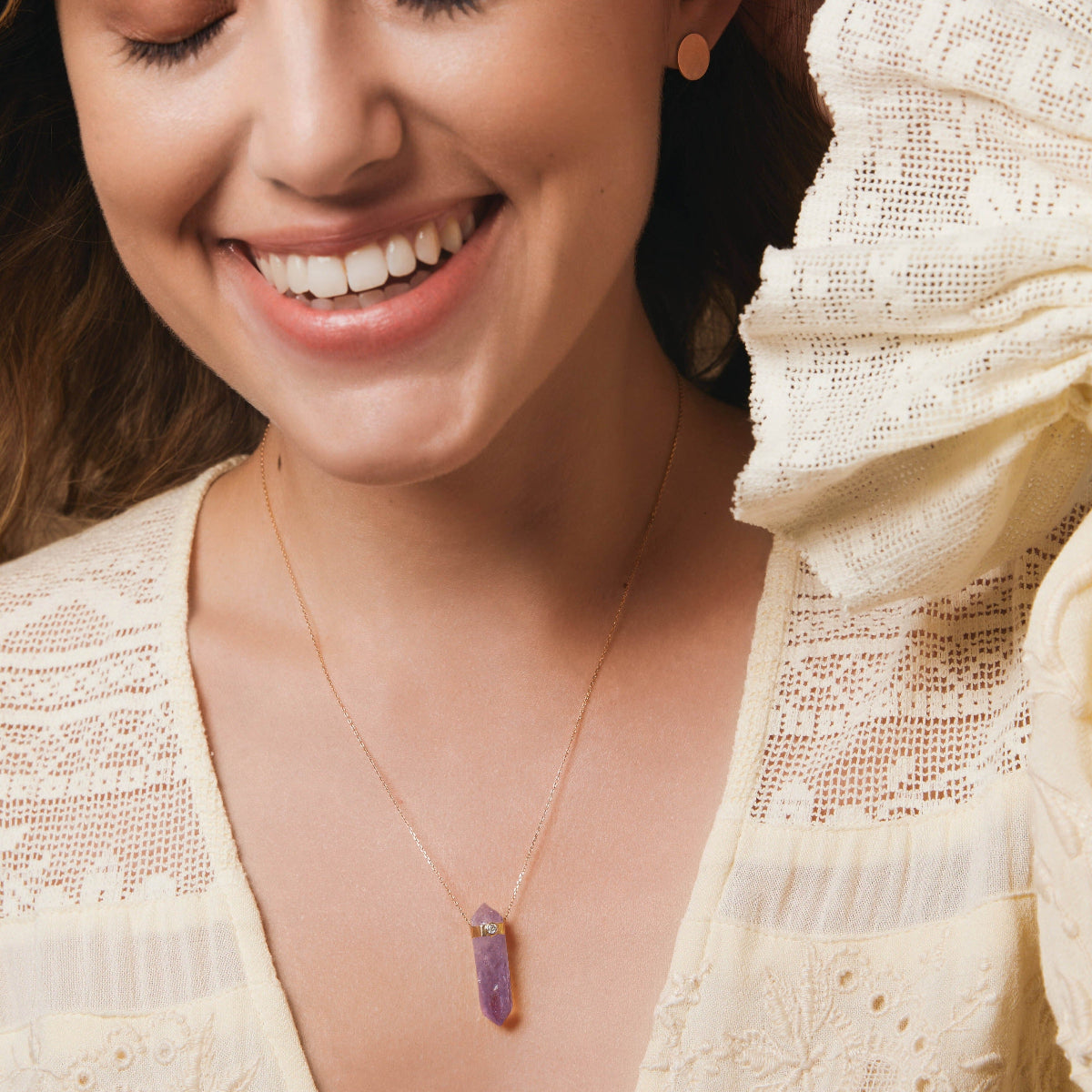A smiling woman wearing the Healing Retreat Necklace and a Solid Eclipse Earring - Small, styled in a light yellow frilly top.