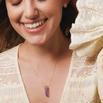 A smiling woman wearing the Healing Retreat Necklace and a Solid Eclipse Earring - Small, styled in a light yellow frilly top.