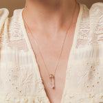 A close-up of a décolletage wearing The Clarity Necklace, styled with a cream top. 