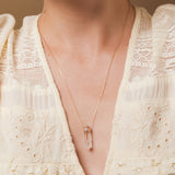 A close-up of a décolletage wearing The Clarity Necklace, styled with a cream top. 