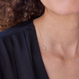 A close-up of a person's neck wearing a yellow gold 14k Gold Asymmetrical Charm Necklace - Pavé Star of David with a cable chain, styled with a navy top. 