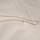 A yellow gold cable chain 14k Gold Asymmetrical Charm Necklace - Star of David against a light grey fabric background.