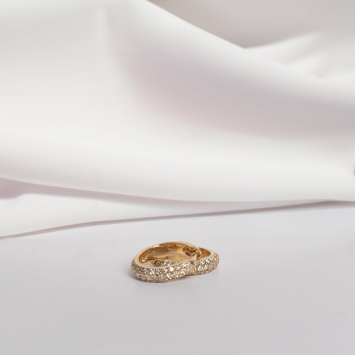 A pair of Pavé Huggies on a white background. 