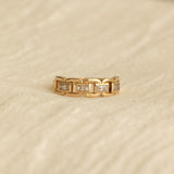 A yellow gold C'est Moi Link Ring on a beige fabric background. 