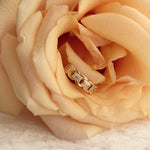 A yellow gold C'est Moi Link Ring nestled in a peach colored rose.