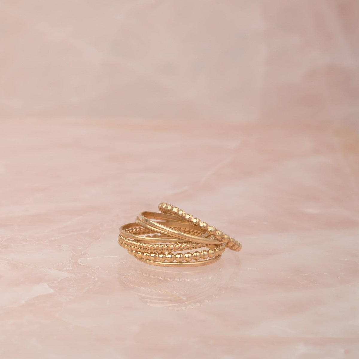 Delicate Trio Stacking Rings on a light pink marble background. 