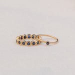 A Birthstone Ring in Sapphire - September and The Iris Bouquet Ring in yellow gold against a light grey background. 